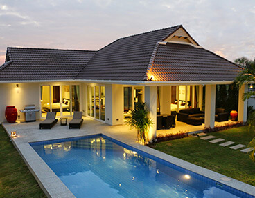 Single-story house with pool and patio area illuminated at twilight