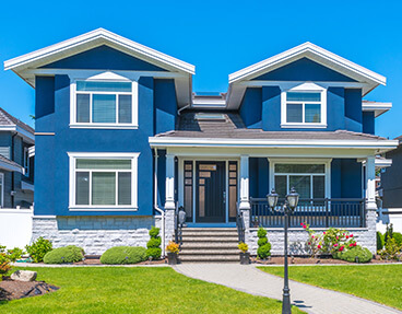 Bright blue two-story suburban house with white trim and a covered front porch